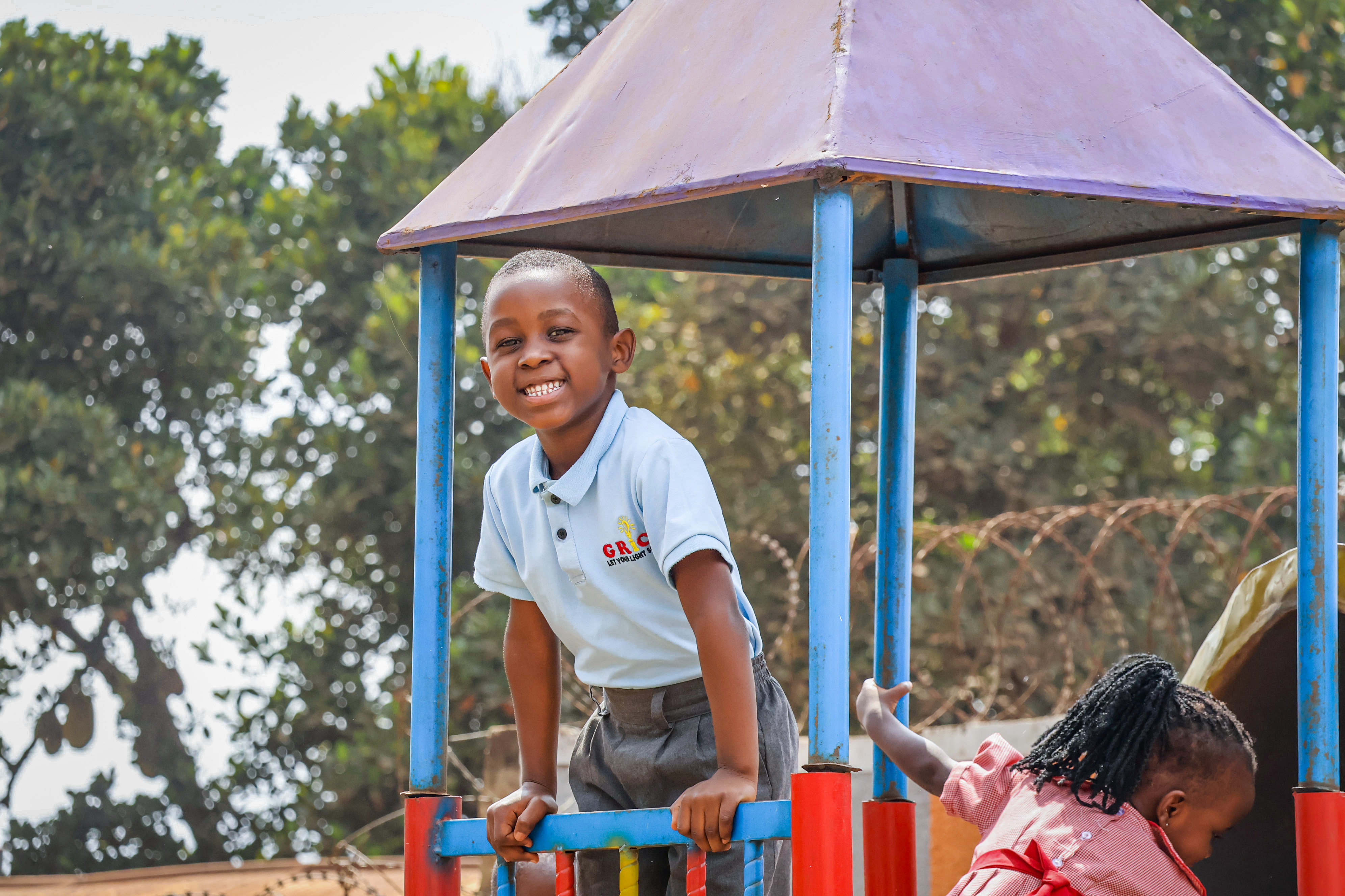 A GRICS learner smiling for the camera on the playground